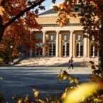 A student traverses Bailey Plaza amid fall foliage.